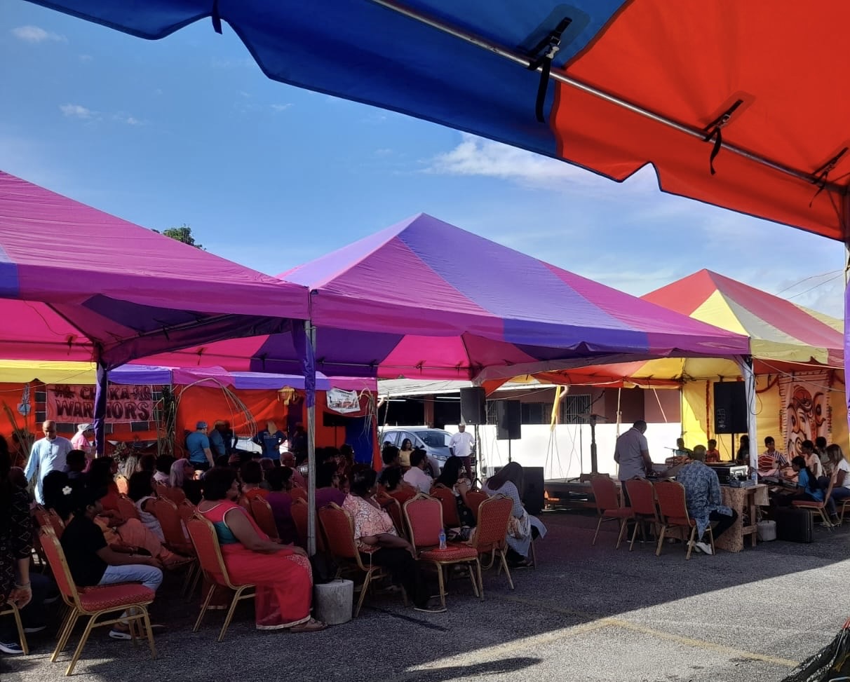 Community members gathered under tents by the sea